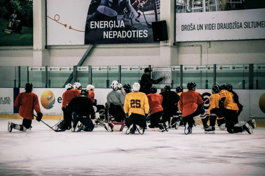 Un coach explique un exercicre à son équipe de hockey - Photo d'Arthur Edelman via Unsplash